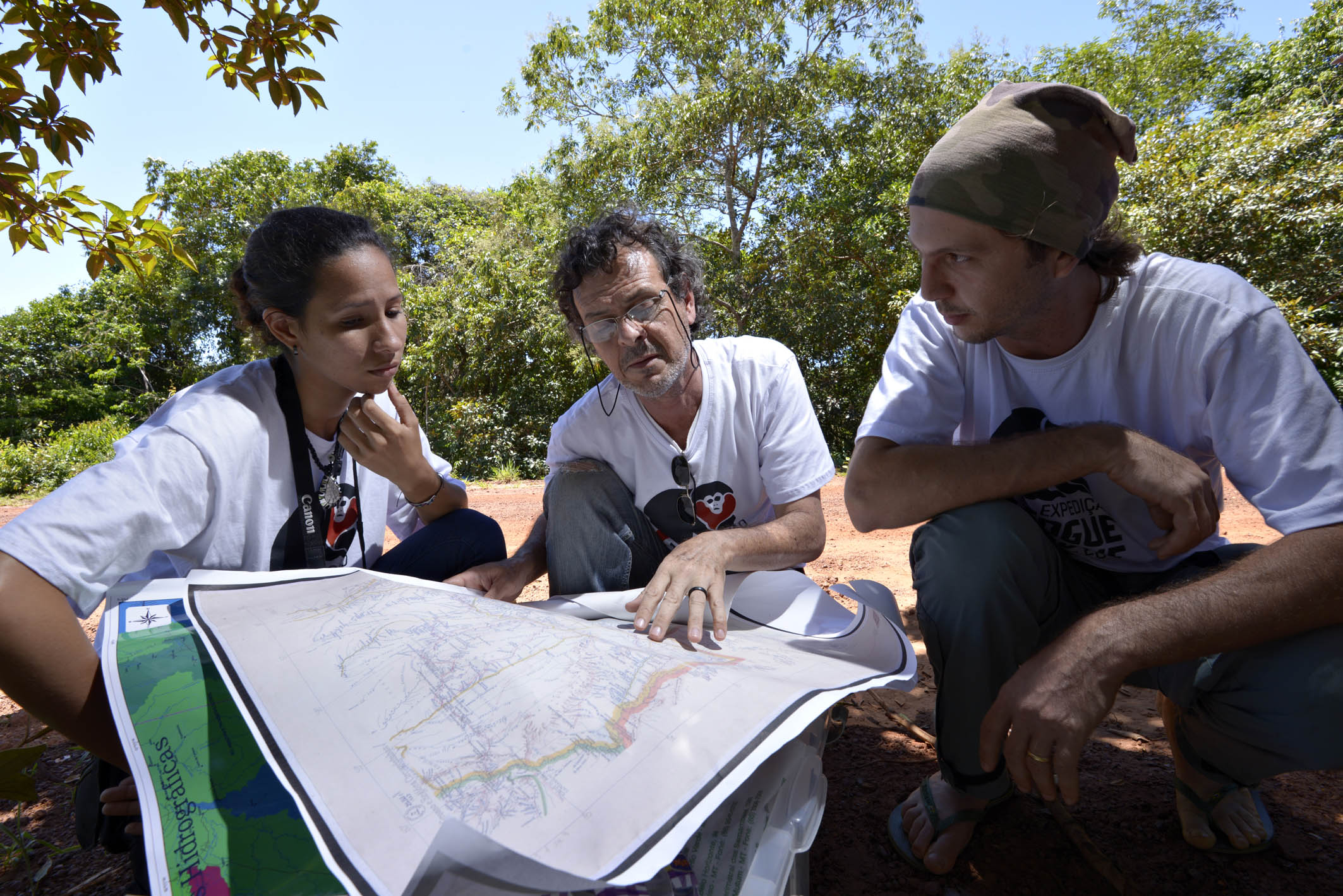 Três dos participantes da expedição conferindo um mapa e possíveis rotas para o trabalho de campo